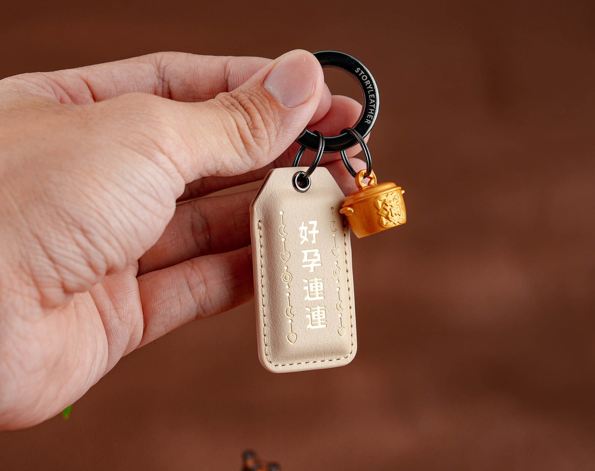 Good News Keeps Coming Amulet clipped as a keychain, held in hand