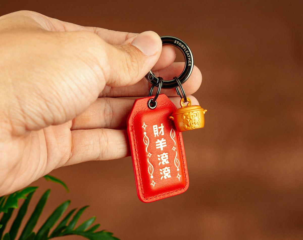 Rolling Wealth Amulet clipped as a keychain, held in hand