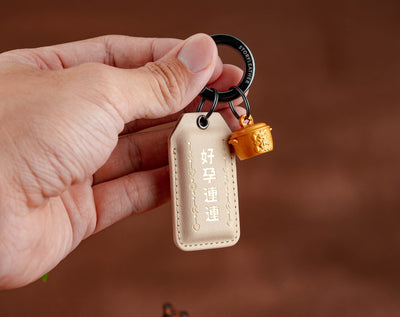 Good News Keeps Coming Amulet clipped as a keychain, held in hand