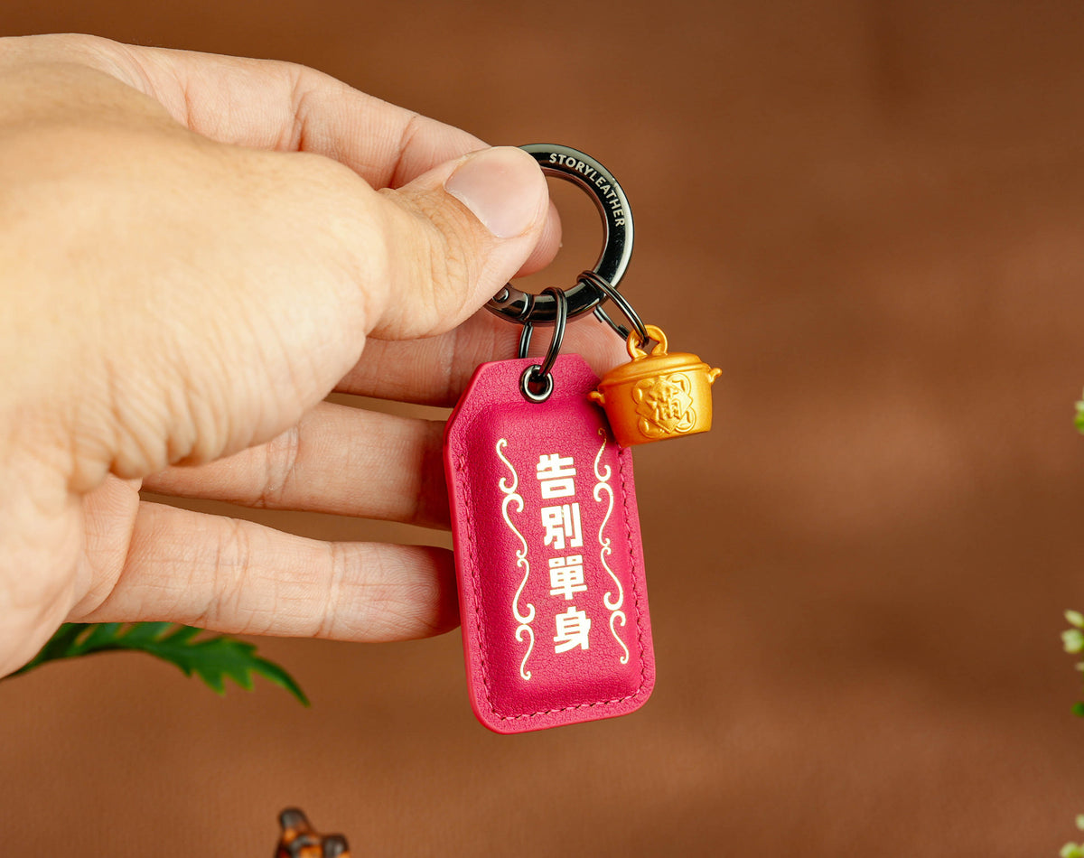 Goodbye Single Amulet rose pink clipped as a keychain, held in hand
